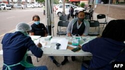 Un professionnel de la santé de la ville de Tshwane mène des exercices de dépistage sur des personnes avant de tester le coronavirus COVID-19 à Pretoria le 17 décembre 2020.