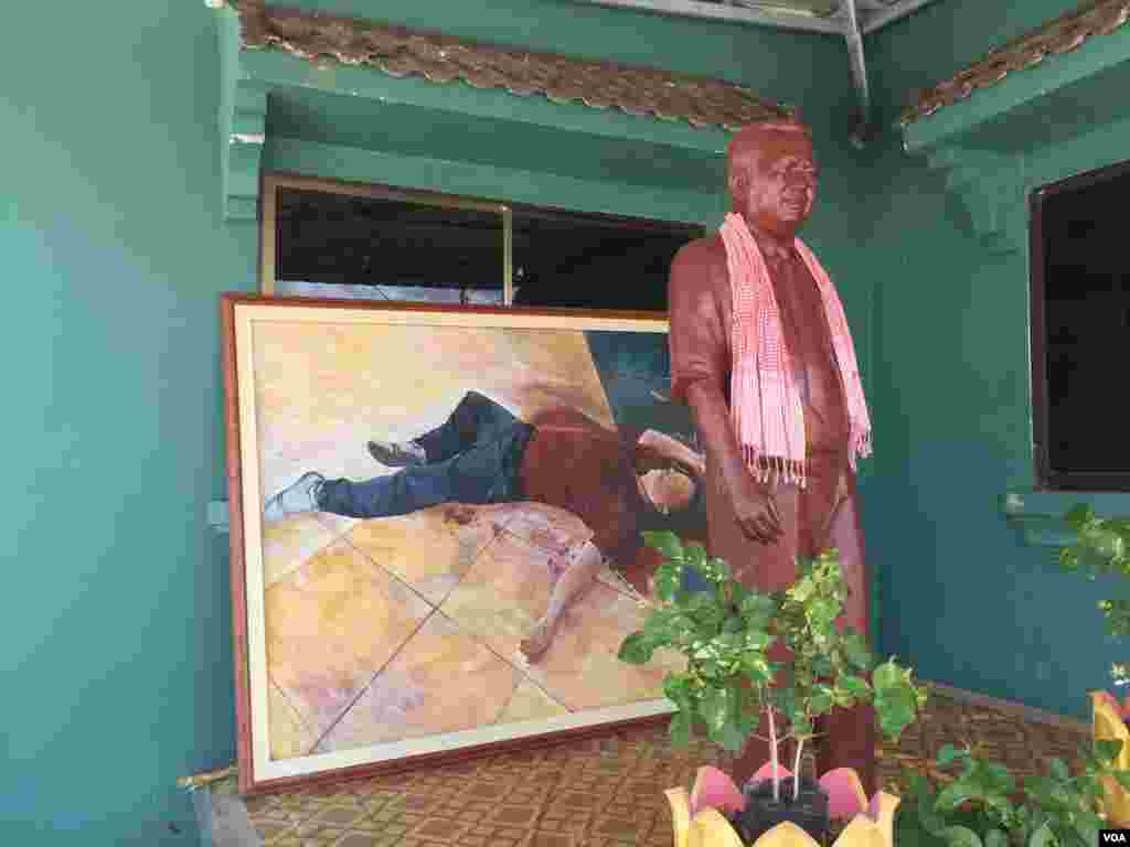 A statue of Kem Ley is displayed in front of a painting that depicts the scene of his death at Caltex gas station last year, Takeo province, Cambodia, July 02, 2017. (Hul Reaksmey/VOA Khmer)