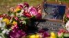 FILE - A rosary covers a photograph of President John F. Kennedy at a marker along Elm Street, where the former president was assassinated, as flowers adorn the memorial on the 60th anniversary of his assassination, Nov. 22, 2023, in Dallas, Texas.