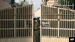 FILE - An Indian police officer is seen closing the gates of a prison in New Delhi, India, in a March 11, 2013, photo.