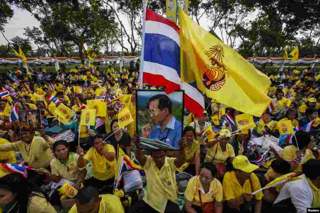 Well-wishers wave flags next to a picture of Thai King Bhumibol Adulyadej as they gather to celebrate his 86th birthday near Klai Kangwon Palace, Hua Hin, Prachuap Khiri Khan province, Dec. 5, 2013.
