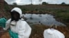 FILE - Waste removal experts work to remove hazardous black sludge from a garbage dump in Abidjan, Ivory Coast.